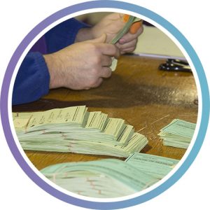 the hands of someone tallying election votes at a table