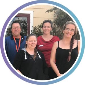 Four participants of a PDCN peer group stand outside the building where they meet, smiling at camera